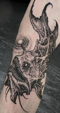 a black and white tattoo on the leg of a person with a fish in it