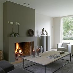 a living room filled with furniture and a fire place in front of a large window