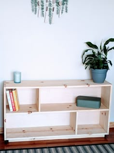 a wooden shelf with plants and books on it next to a wall mounted planter