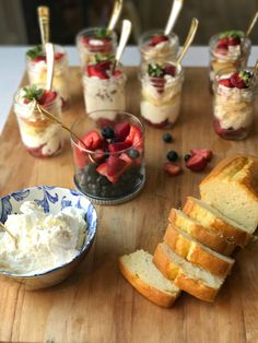 there are many desserts on the table with strawberries and blueberries in jars