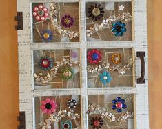 an old window with buttons and flowers in it