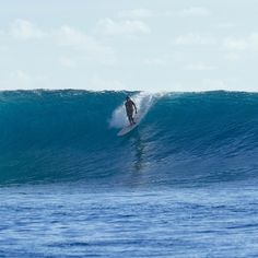 a man riding a wave on top of a surfboard in the middle of the ocean