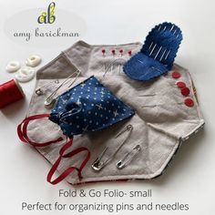 an assortment of sewing supplies on top of a piece of cloth with text overlay that reads fold & go foll - small perfect for organizing pins and needles