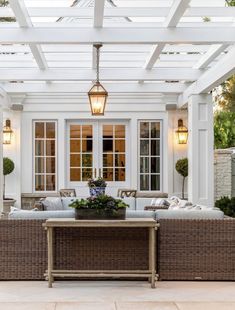 an outdoor living area with wicker furniture and white walls, covered in glass roofing