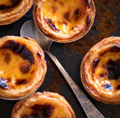 four small pies on a table with spoons