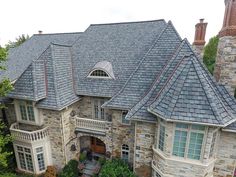 an aerial view of a stone house with gray roofing and white trimmings