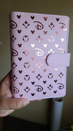 someone is holding up a pink passport case with mickey mouse symbols on the front and side