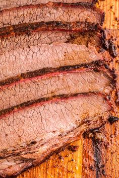 sliced brisk roast on a cutting board with sauce and seasoning sprinkles