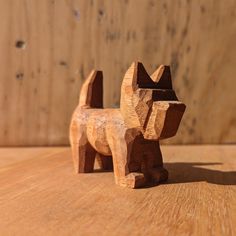 a wooden dog figurine sitting on top of a wooden table next to a wall