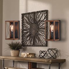 a wooden table topped with a plant next to two wall sconces