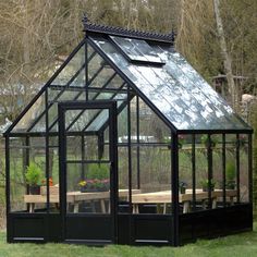 a small black greenhouse sitting on top of a lush green field