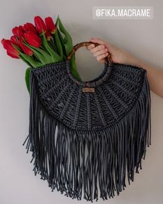 a woman's hand holding a woven purse with flowers in it