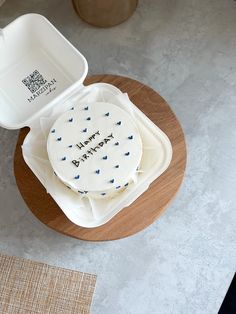 a happy birthday cake sitting on top of a wooden table next to a white container