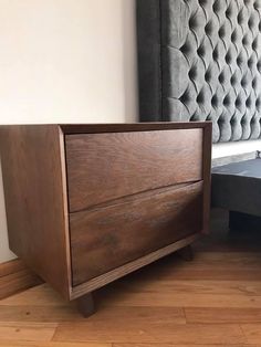 a wooden bed frame sitting on top of a hard wood floor next to a wall