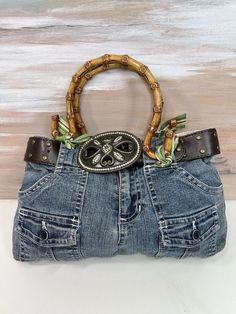 the purse is made out of jeans and has a wooden handle with an animal head on it