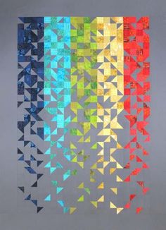 a multicolored quilt hanging from the side of a wall with multiple triangles on it