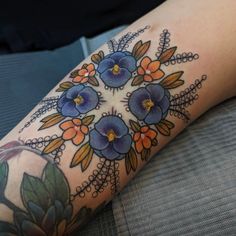 a woman's arm with flowers and leaves tattooed on the side of her leg