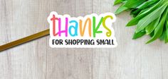 there is a sticker that says thanks for shopping small on the table next to some leaves