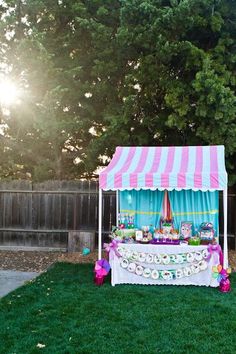 a pink and white tent sitting on top of a lush green field