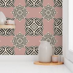 a pink wall with black and white designs on the wall next to two vases