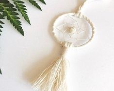 a white dream catcher sitting on top of a table next to a plant with green leaves