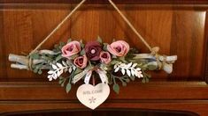 a welcome sign hanging on the front of a piano with pink flowers and greenery