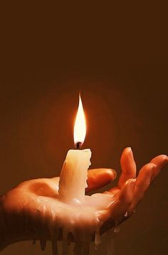 a person holding a lit candle in their hand with water dripping from the top and bottom