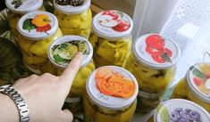 a person pointing at jars filled with pickles