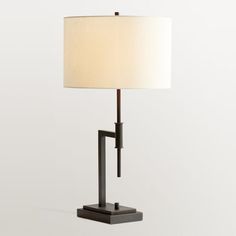 a table lamp with a white shade on it and a black frame around the base