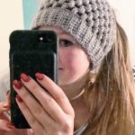 a woman is taking a selfie with her cell phone while wearing a knitted hat