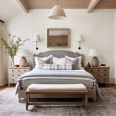 a bedroom with a bed, dressers and two lamps on either side of the bed