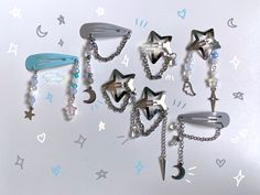 several hair clips with chains attached to them on a white surface, surrounded by stars and moon shapes