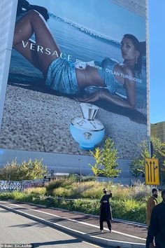 a large advertisement on the side of a building in front of a woman's body