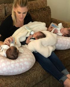 a woman sitting on a couch with three babies