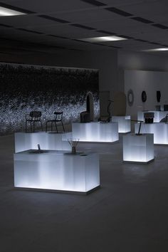 several illuminated cubes in an empty room with chairs and tables on the floor at night