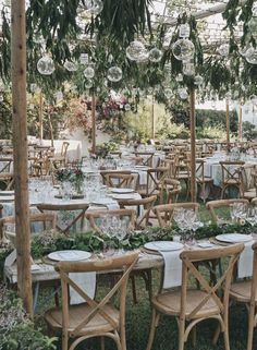 tables and chairs are set up for an outdoor wedding reception in the garden with hanging glass globes