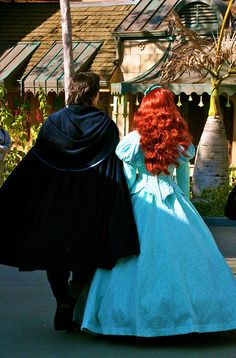 two people dressed as princesses walking down the street