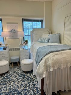 a white bed sitting in a bedroom next to a blue and white rug on top of a wooden floor