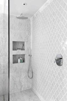 a bathroom with a shower, sink and toiletries in white marble tile on the walls