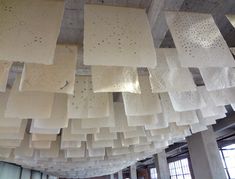 the ceiling is made up of white squares and square pieces of paper hanging from it