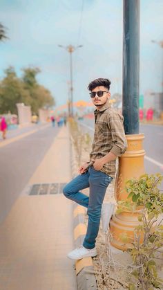 a man leaning on a pole next to a street