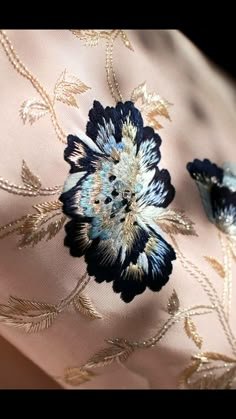 an embroidered fabric with blue and gold flowers on it