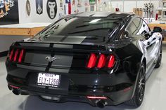 the rear end of a black mustang in a garage