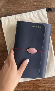 a person is holding a book with a pink bead on it