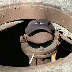 a hat is sitting in the middle of a metal pipe with some rust on it