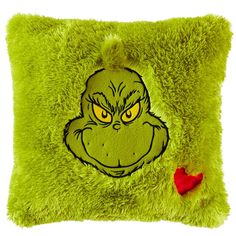 a green pillow with an angry grin face on it's side and a red heart in the middle