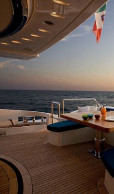 the sun is setting over the ocean on a boat with blue seats and a wooden table