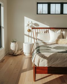 a bed sitting in a bedroom next to two windows on top of a hard wood floor