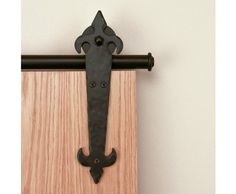 an iron door handle is mounted on the side of a wooden door with black hardware