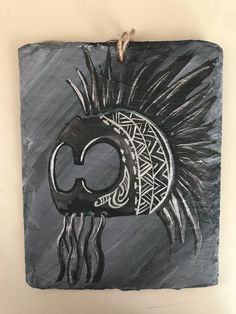 a black and white drawing of a native american headdress on a slate plaque